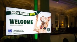 Screen showing a dog holding its paw up and a banner saying 'Welcome' in front of an empty dancefloor.