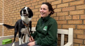 Animal Welfare Carer, Anna, smiling with Alan the collie