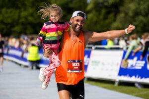 adult holding child running in the festival